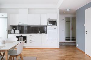 cocina con armarios blancos, mesa y sillas en Nordic Design Apartment City Center, en Rovaniemi