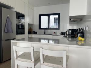 una cocina blanca con 2 sillas blancas y una barra en Villa Sea View, en Arco da Calheta