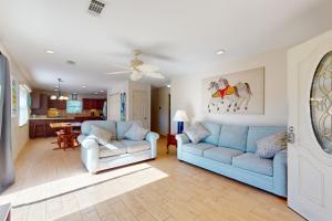 a living room with two blue couches and a kitchen at Keepin' it Reel in Pensacola Beach