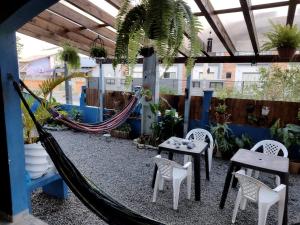 a patio with a hammock and tables and chairs at Hostel Da Ilha De Sao Francisco Do Sul in Marechal Luz