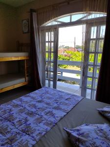 a bedroom with a bed and a large window at Hostel Da Ilha De Sao Francisco Do Sul in Marechal Luz