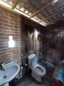 a brick bathroom with a toilet and a sink at Amaranthe Beach Cabanas in Galle