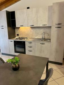 a kitchen with white cabinets and a table with a potted plant at Residence la Lucciola in Lonato