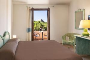 a bedroom with a bed and a view of a patio at Hotel Sole Mare in Baja Sardinia