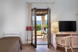 - une chambre avec un lit et un bureau avec une télévision dans l'établissement Hotel Sole Mare, à Baja Sardinia