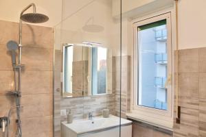 een badkamer met een wastafel en een douche met een raam bij Duomo a 15 minuti - Lussuoso appartamento in Milaan