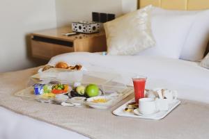 bandeja con comida y bebida en la cama en Arabella Premium Residence - New Cairo, en El Cairo