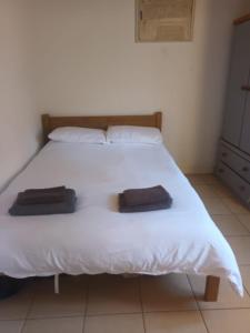 a bedroom with a white bed with two towels on it at Private Bedrooms in Quaint Oxfordshire Village Cottage in Wantage