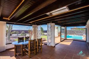 Un patio con mesa y sillas y una piscina. en Villa Sara, en Playa Blanca
