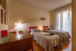 a bedroom with two beds and a desk and a window at Casa Gilda in Sesto Fiorentino