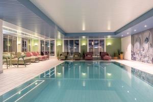 una piscina en el vestíbulo del hotel con sillas y mesas en Central Sporthotel Davos, en Davos