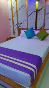 Bett mit blauer und lila Bettwäsche und Kissen in der Unterkunft Hotel sweta villa & banquet hall in Bankipur