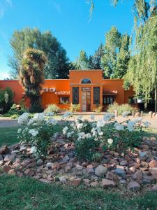 una casa naranja con un jardín de rocas delante de ella en Finca La Saucina Casa de Campo en Tunuyán