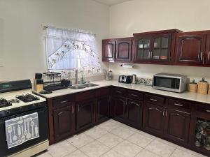 a kitchen with wooden cabinets and a sink and a microwave at St Bess Comfort Style in Black River