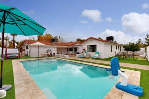 a swimming pool in front of a house with an umbrella at Encanto Dreams in Phoenix