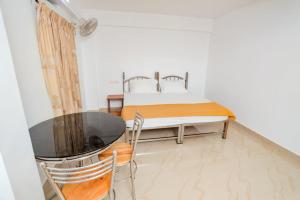 1 dormitorio con 1 cama, mesa y sillas en EL LORA RESlDENCY, en Munnar