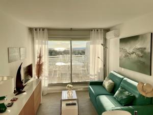 een woonkamer met een groene bank en een balkon bij PGH N25 - Vue Mer, Première Ligne & Parking Privé in La Grande-Motte