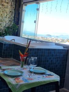 a table with two glasses and a table with a bath tub at Suite Bela vista Muriqui Cantinho Feliz in Mangaratiba