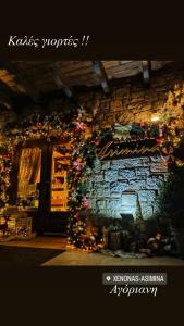 Una pared de ladrillo con luces de Navidad y un árbol de Navidad en Asimina Guesthouse, en Eptalofos