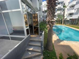 a house with a palm tree next to a swimming pool at Au Cœur Des Sables D’or - Harhoura in Temara