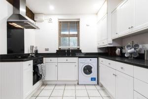 a kitchen with white cabinets and a washer and dryer at Stunning Old Forge with Huge Balcony in Leamington Spa