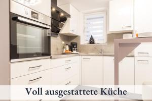 una cocina blanca con armarios y electrodomésticos blancos en RelaxApartment 15 Massagesessel SmartTV Küche, en Biberach an der Riß