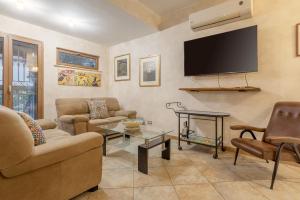 ein Wohnzimmer mit Sofas und einem TV an der Wand in der Unterkunft Appartamento in villa con piscina in Palermo