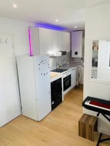 cocina con armarios blancos y nevera blanca en Studio cosy au cœur de Paris en París