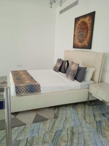 a white bed with pillows and a painting on the wall at As sifah in As Sīfah