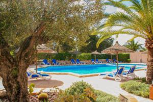 a swimming pool with blue chairs and umbrellas at La Ardilla in Cala Santanyi