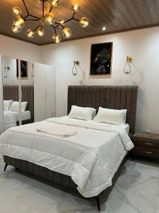 a bedroom with a large bed with white sheets and lights at Keur Buur in Dakar