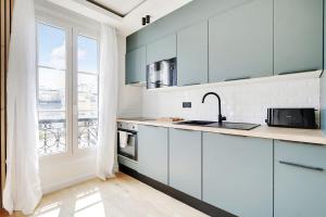 eine Küche mit weißen Schränken und einem großen Fenster in der Unterkunft OLYMPIADES - PATAY Beautiful apartment in Paris