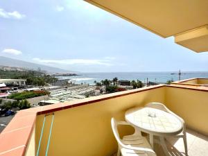 een balkon met een tafel en stoelen en de oceaan bij Apartmento a 150m de playa, con piscina climatizada in Puerto de la Cruz