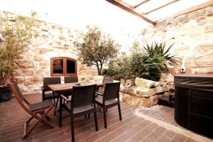 un patio con tavolo e sedie in legno di Luxury House of Character Golden Bay/Manikata. a Ix-Xagħra l-Ħamra