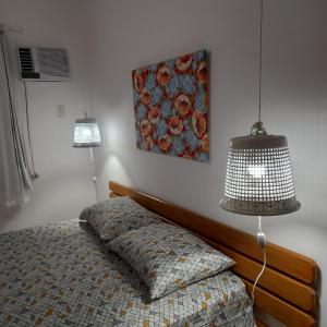 a bedroom with a bed with a lamp and a painting at Apartamento inteiro n.24 in Porto Seguro