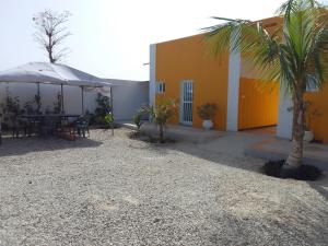 ein Haus mit einem Tisch, einem Sonnenschirm und einer Palme in der Unterkunft Hôtel Colibri in Niaga