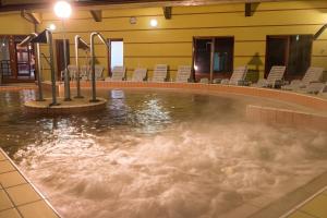 una piscina de agua con sillas en un edificio en Vulkán Wellness Hotel & Camping en Celldömölk