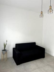 eine schwarze Couch in einem Zimmer mit Pflanze in der Unterkunft Casa a 400 M de la playa in Mar del Plata