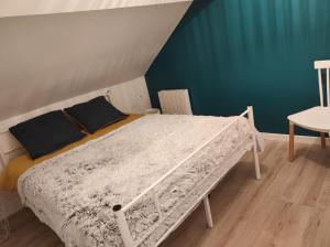 ein weißes Bett in einem Zimmer mit blauer Wand in der Unterkunft la maison du bonheur in Alençon