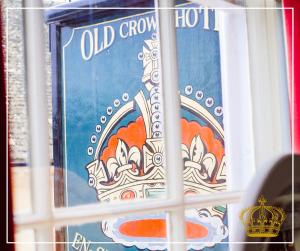 a window with a blue sign with a crown on it at The Old Crown Coaching Inn in Faringdon
