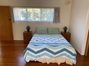 1 dormitorio con 1 cama con manta azul y blanca en By the Seashaw - Hosted by Lorna, Michael & Katja, en Parapara 