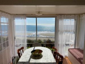 a dining room with a table and a view of the ocean at By the Seashaw - Hosted by Lorna, Michael & Katja in Parapara 