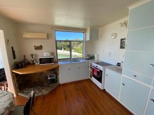 una cocina con armarios blancos y una encimera con ventana en By the Seashaw - Hosted by Lorna, Michael & Katja, en Parapara 