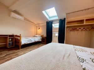 une chambre avec deux lits et une lucarne dans l'établissement La Traverse - au pied de la Cité Médiévale - Clim et terrasse, à Carcassonne