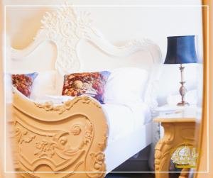 um quarto com uma cama branca e uma mesa com um candeeiro em The Old Crown Coaching Inn em Faringdon