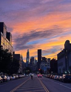 a city street at sunset with cars parked at Room in a 2 Bedrooms apt. 10 minutes to Time Square! in West New York