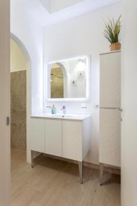 uma casa de banho branca com um lavatório e um espelho em The Tropical Place em Milão