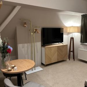 ein Wohnzimmer mit einem TV und einem Tisch in der Unterkunft Hotel Grand Canal in Delft
