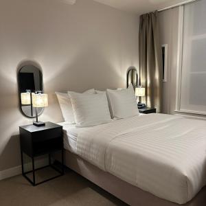 a bedroom with a large white bed with two lamps at Hotel Grand Canal in Delft