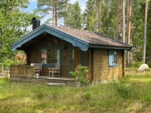 Cabaña de madera pequeña con porche y silla en Timrad stuga i kanten av skogen med SPA möjlighet, en Mullsjö